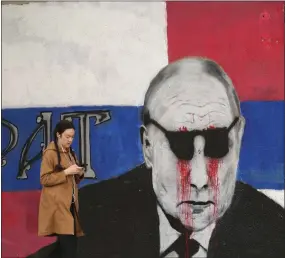  ?? DARKO VOJINOVIC — THE ASSOCIATED PRESS ?? A woman passes by a mural depicting the Russian President Vladimir Putin that has been vandalized with paint, in Belgrade, Serbia, on Saturday..