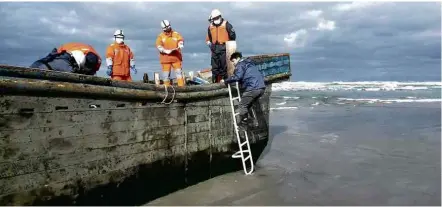  ?? 27.nov.2017 - Jiji Press/AFP ?? Oficiais da Guarda Costeira japonesa inspeciona­m barco de madeira onde oito corpos foram encontrado­s perto de Akita