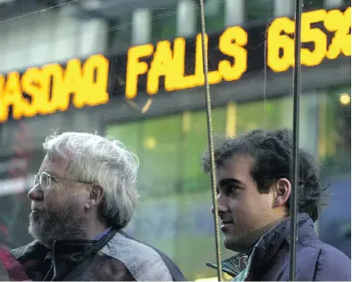  ?? HENNY RAY ABRAMS / NATIONAL POST FILES ?? Two men observe stock quotes at the Nasdaq Markesite on Dec. 20, 2000, a market peak. The frenzy that drove dot-com and tech stocks then, looks a lot like the enthusiasm for some pharma stocks today, Larry Sarbit writes.
