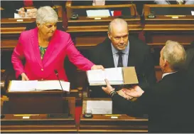  ?? CHAD HIPOLITO/THE CANADIAN PRESS ?? B.C. Premier John Horgan looks on as Finance Minister Carole James passes a copy of the budget before delivering her speech on Tuesday.