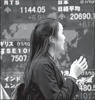  ?? AP/KOJI SASAHARA ?? A woman passes an electronic stock board at a securities firm Friday in Tokyo. Shares were mostly higher in Asia on Friday, with the Nikkei 225 stock index rising 0.3 percent.