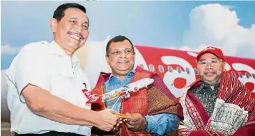  ??  ?? Going even further: Fernandes (centre) presenting an AirAsia model aeroplane to Luhut (left) after launching the new route from Kuala Lumpur to Silangit. With them is Kamarudin.