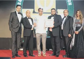  ??  ?? Ali Hussain, centre, collecting his award in London.