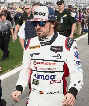  ?? — AP ?? Big challenge: Fernando Alonso of Spain walking down the pit lane to his car before the start of the IMSA 24-hour auto race at Daytona Internatio­nal Speedway on Saturday.