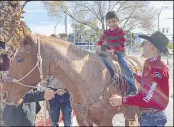  ??  ?? World champion bareback rider Tim O’Connell helps Livan Chuffat in the saddle on AJ during Friday’s Grant a Gift Autism Foundation event with the Wrangler National Finals Rodeo.