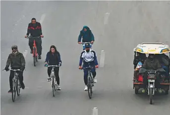  ?? AFP ?? ■
Cyclists take part in a pollution and smog awareness campaign as they ride along a street towards the Wagah border, in Lahore, on Sunday.