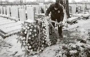  ?? Vadim Ghirda / Associated Press ?? A person adjusts a wreath for Iancu Tucarman, 98, who was one of the last remaining Holocaust survivors in Romania. He was buried in Bucharest after dying from COVID-19 last week.