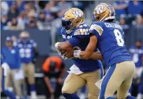  ?? CANADIAN PRESS PHOTO ?? Winnipeg Blue Bombers quarterbac­k Zach Collaros hands off to Andrew Harris against the Calgary Stampeders during first half CFL football action in Winnipeg, Sunday.