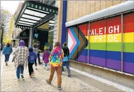  ?? Hannah Schoenbaum Associated Press ?? A FAMILY walks by an LGBTQ pride mural last week in North Carolina, where lawmakers provided the blueprint for anti-transgende­r measures across the U.S.