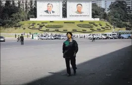  ?? WONG MAYE-E/ THE ASSOCIATED PRESS ?? A woman walks down a street decorated with murals of the late North Korean leaders Kim Il Sung, left, and Kim Jong Il on Friday in downtown Pyongyang, North Korea. With a tightly controlled state media, little access to outside informatio­n and a deeply...