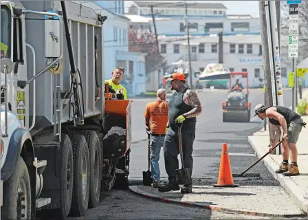  ?? SEAN D. ELLIOT/THE DAY ?? Workers with Ed French and Son, Inc., Asphalt Paving, lay down a layer of blacktop Thursday on Cottrell St. in downtown Mystic. The paving work is part of a plan to convert the street’s traffic pattern to one-way starting next week.