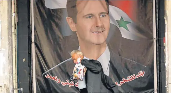  ?? LOUAI BESHARA / AFP ?? Un hombre pasa delante de un gran cartel con el rostro del presidente sirio, Bashar el Asad, en Damasco