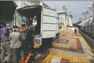  ??  ?? Volunteers help to load food in a van for distributi­on.