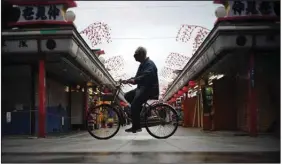  ?? (AP/Eugene Hoshiko, File) ?? A bicyclist rides through an empty Tokyo shopping arcade in January. While many economists believe global inflation has become a bigger problem than covid-19, soaring prices are almost nonexisten­t in Japan. The Bank of Japan is forecastin­g 0% inflation for the fiscal year that ends in March.