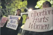  ?? JOHN ROARK/ATHENS BANNER-HERALD VIA TE ASSOCIATED PRESS ?? File-Ariana Marsh, center, and Katie Davis, right, participat­e in a pro-life candleligh­t vigil organized by Students for Life at UGA held to protest Roe v. Wade at the University of Georgia Arch, on Tuesday, Jan. 24, 2017, in Athens, Ga.