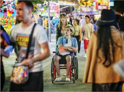  ?? LEAH HENNEL ?? Three months after the crash, Straschnit­zki and Erika Burns take in the Calgary Stampede midway in 2018.