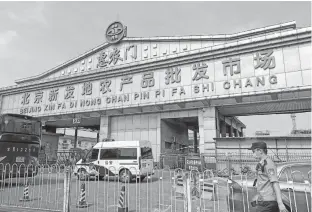  ?? REUTERS ?? A police officer wearing a face mask watches an entrance of the Xinfadi wholesale market, which has been closed for business after new coronaviru­s infections were detected, in Beijing Saturday.