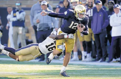  ?? PAUL SANCYA/AP ?? Notre Dame quarterbac­k Tyler Buchner tries to break the tackle of Navy cornerback Jamal Glenn on Saturday.