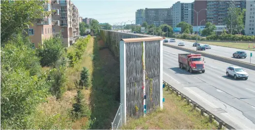  ?? - La Presse canadienne: Ryan Remiorz ?? Un mur antibruit sépare une autoroute et un quartier résidentie­l.