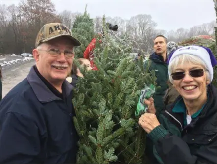  ?? BY PAUL POST ?? Vietnam veteran Robert Van Pelt, left, helps Ellms Family Farm co-owner Sally Ellms move one of the 130trees donated by area growers.