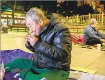  ??  ?? HSU CHONG-CHI, 64, uses an inhaler to help relieve his asthma before bedding down for the night at Bangka Park. The city imposes a strict schedule on residents like Hsu.