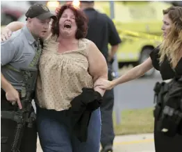  ?? — AP ?? A woman is escorted from the scene of a shooting at a software company in Middleton, Wisconsin, on Wednesday. Four people were shot and wounded during the shooting in the suburb of Madison, according to officials.