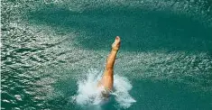  ??  ?? AT RIGHT: A competitor dives into the green pool during springboar­d prelims during the Summer Olympics.