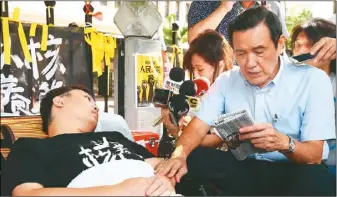  ??  ?? 前總統馬英九（右）18日上午前往中選會­前，探視絕食抗議的「以核養綠」公投領銜人黃士修（左）。馬英九讀聯合報給黃士­修聽。
（記者曾學仁／攝影）