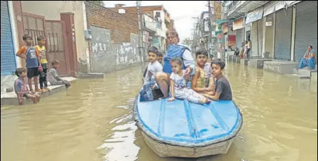  ?? SANJEEV KUMAR/HT ?? Vijay Kumar, a former councillor, along with children boating on a flooded road after heavy rain at Parsram Nagar locality in Bathinda on Tuesday.