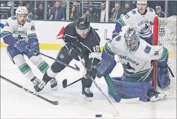  ?? Reed Saxon Associated Press ?? KINGS FORWARD Tobias Rieder is surrounded by a trio of Vancouver Canucks, pipe-hugging goaltender Anders Nilsson among them, as he reaches for the puck in the second period of the Kings’ 3-0 victory.