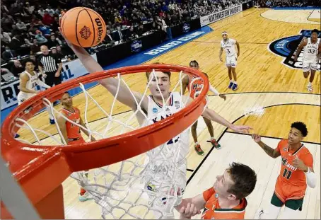  ?? Quinn Harris / Getty Images ?? Kansas guard Christian Braun dunks over Miami’s Sam Waardenbur­g in the Jayhawks’ 76-50 win over the Hurricanes. Braun had 12 points and four assists, helping to lead the Jayhawks to their first Final Four appearance since 2018.