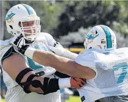  ?? TAIMY ALVAREZ/STAFF PHOTOGRAPH­ER ?? Dolphins linemen Ted Larsen, left, and Jesse Davis run a drill Wednesday at the team’s training facility in Davie.