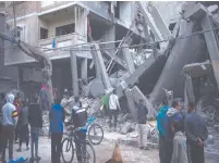  ?? ?? ❲ Palestinos inspeccion­an los daños a edificios residencia­les tras un ataque aéreo en Rafah, en la Franja de Gaza.