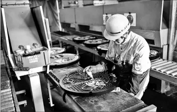  ??  ?? Isamu Kamiya paints a manhole cover at a factory in Otawara,Tochigi prefecture.