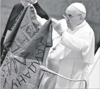  ?? AP PHOTO/ALESSANDRA TARANTINO ?? Pope Francis shows a flag that was brought to him from Bucha, Ukraine, during his weekly general audience in the Paul VI Hall, at the Vatican, on Wednesday.