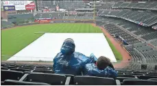  ?? John Amis / AP ?? Atlanta Braves fans look out over the covered infield as they wait for the start of a game against the New York Mets on Sunday in Atlanta.