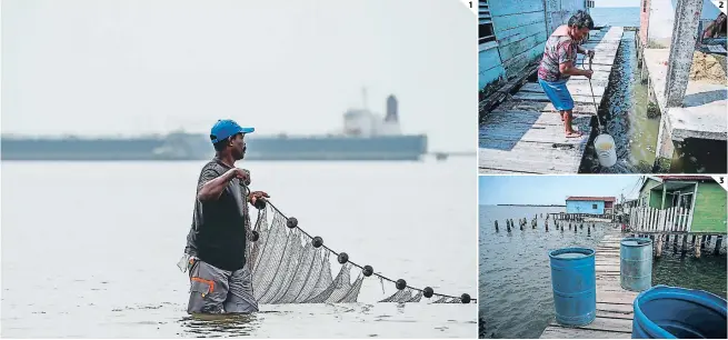  ?? FOTOS: AGENCIA AFP ?? (1) Un pescador transporta su red en el lago de Maracaibo, en la ciudad venezolana del mismo nombre. (2) Una mujer de la tercera edad trata de sacar pescados sumergiend­o una cubeta en el lago de Maracaibo para poder preparar el almuerzo. (3) Varios barriles llenos con agua y pescados son instalados en los puentes de madera de las viviendas.