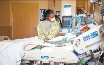  ?? Francine Orr Los Angeles Times ?? GUADALUPE RODRIGUEZ comforts her husband, Alexander Frazier, in an L.A. hospital on Jan. 26, 2022. Frazier had COVID and diabetes and died the next day. A year later, COVID is still taking a toll in L.A. County.