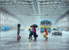  ?? PTI ?? People cross the road at the Howrah Bridge amid monsoon rains on Thursday