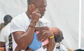  ?? TREVOR HUGHES/USA TODAY ?? Hurricane Dorian evacuee Cecil Grant, 31, cradles his daughter, Yalissa, 7 months, while he makes a phone call at a shelter in Nassau.