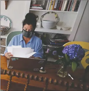  ??  ?? Truax looks over her recent work while seated at her writing table.