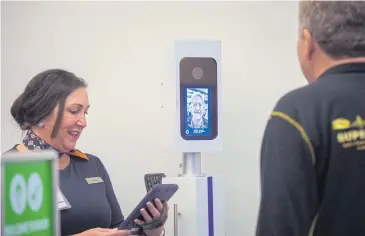  ?? THE NEW YORK TIMES ?? A JetBlue crew member in Boston using facial recognitio­n software to clear a passenger to board a flight to Aruba.