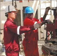  ??  ?? Li teaches a worker to operate drilling equipment in Sudan.