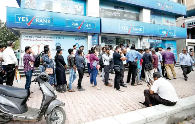  ?? Reuters ?? ↑ Customers wait outside a Yes Bank branch to withdraw money in Ahmedabad, India.