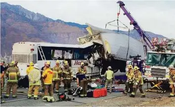  ?? AP ?? Emergency workers tow away the remains of the bus and truck. Officials said the bus did not have seat belts. As a result, some of the victims suffered facial injuries involving soft tissue and bones and may require plastic surgery.