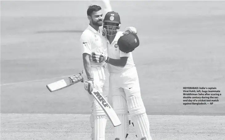  ?? AP ?? HDYERABAD: India’s captain Virat Kohli, left, hugs teammate Wriddhiman Saha after scoring a double century during the second day of a cricket test match against Bangladesh.—