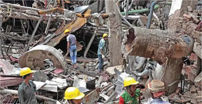  ??  ?? GAZIPUR: Bangladesh­i rescuers stand on the debris after a Monday evening boiler explosion at a garment factory owned by export-oriented Multifabs Ltd. at Kashimpur area. — AP