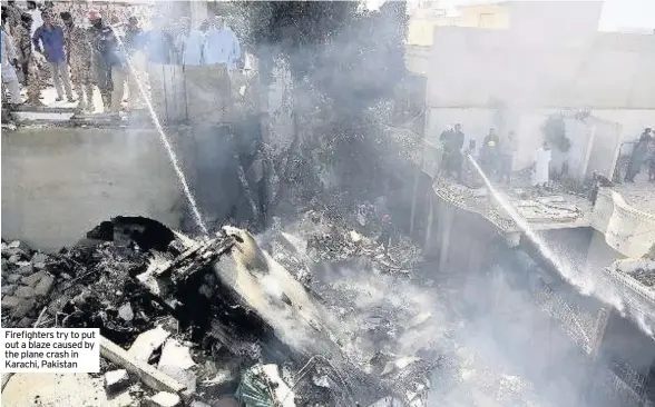  ??  ?? Firefighte­rs try to put out a blaze caused by the plane crash in Karachi, Pakistan