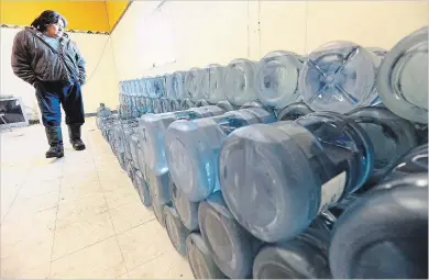  ?? CANADIAN PRESS FILE PHOTO ?? Stewart Redsky of Shoal Lake 40 First Nation walks past one week’s worth of water bottles in the community’s water storage room in 2015. A new study suggests technologi­cal advances in water monitoring could reduce significan­tly the number of...