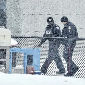  ?? FRANK GUNN/THE CANADIAN PRESS ?? Two police officers walk around Pauline Johnson Junior Public School in Toronto on Monday. A Toronto police investigat­ion has concluded that an incident reported by an 11-year-old girl who claimed her hijab was cut by a scissors-wielding man as she...